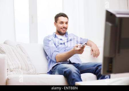 lächelnder Mann mit TV-Fernbedienung zu Hause Stockfoto