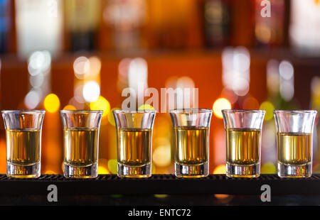 Variation der harte alkoholische Schüsse auf Bartheke serviert. Flaschen auf Hintergrund Unschärfe Stockfoto