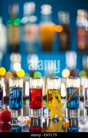 Variation der harte alkoholische Schüsse auf Bartheke serviert. Flaschen auf Hintergrund Unschärfe Stockfoto