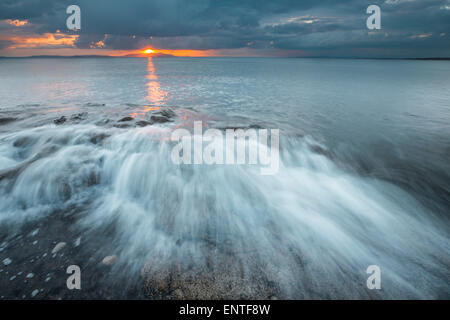 Strand Prestwick, Ayrshire, Schottland, Großbritannien mit Isle of Arran in der Ferne-Wellen bei Sonnenuntergang Stockfoto