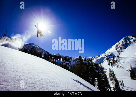 Ein Mann macht einen Backflip aus einen Sprung im Brighton Utah Backcountry. Stockfoto