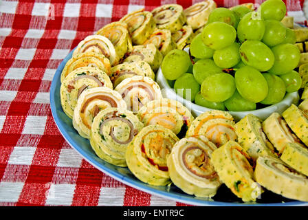 Grüne Trauben mit Fleisch und Käse Spirale Vorspeisen auf rot-weiß karierte Tischdecke. Stockfoto