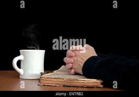 Gebet auf eine verschlissene Bibel mit weißen Kaffeetasse gefaltet Frauenhand. Stockfoto