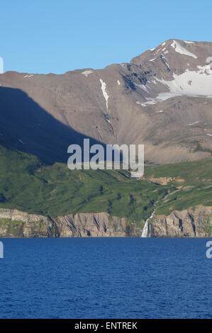 Schnee, mit einer Kappe, Fjord, Meer, Wasserfälle, Küste, Schnee, mit einer Kappe, Fjord, Küste, führt, zu, Meer, Felsen, und, Gras, PortraitNaturbeleuchtung, Naturlandschaft, UNF Stockfoto