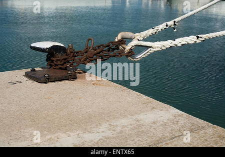 Industrielle rostige Kette und Knopf Closeup auf Steg mit Wasser festmachen. Mallorca, Balearen, Spanien. Stockfoto