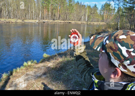 Der junge mit dem Kompass. Die magnetischen Kompass in der Hand des jungen auf dem Hintergrund des Flusses Frühling. Stockfoto