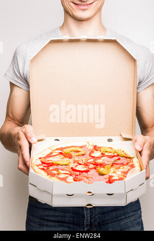 Junger Mann bietet Pizza Diabola. Pizza Lieferung Kurier hält zwei Boxen in Händen Stockfoto