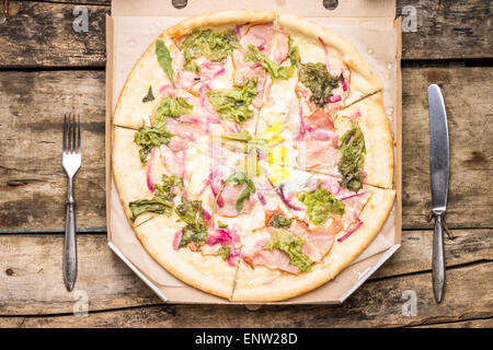 Fast-Food Essen Hintergrund. Pizza in Karton mit Besteck auf Holztisch. Top View-Bild Stockfoto