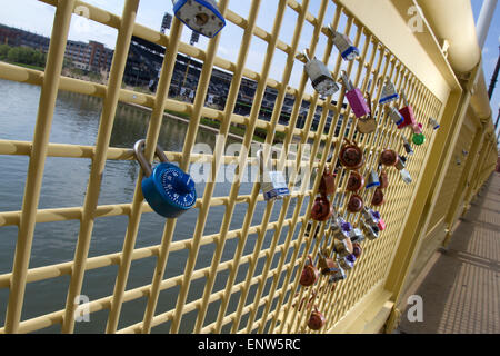 Pittsburgh, PA, USA - 5. Mai 2015: Schlösser der Liebe am Geländer der Roberto Clemente Bridge mit PNC Park im Hintergrund über Alleghe Stockfoto