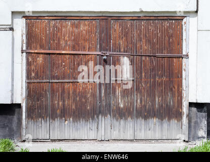 Altes Holztor in weißen Betonwand von einem gewöhnlichen Wohnhaus gesperrt Stockfoto