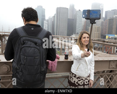 Junge Frau, die ein Selbstporträt auf der Brooklyn Bridge in New York City 2015. Stockfoto