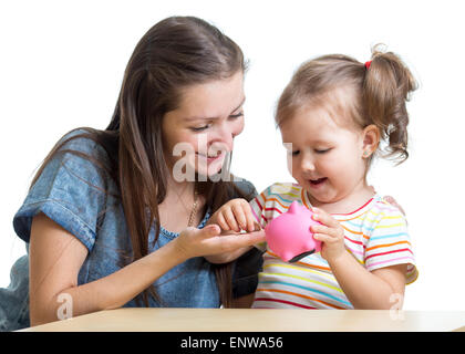 Mutter und Tochter legen Münzen ins Sparschwein