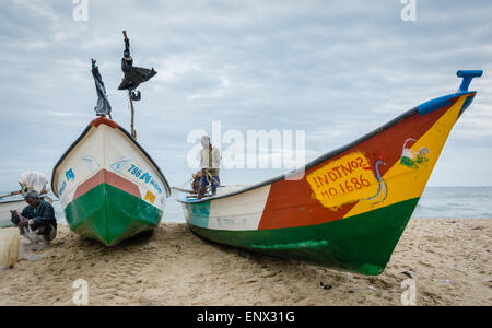 Indische Fischer tendenziell ihre Netze durch ihre Boote am Strand von Marina, Chennai, Indien Stockfoto