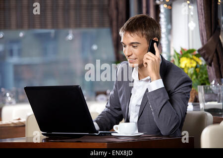 Geschäftsmann mit dem Laptop verwendet eine mobile Kommunikation im café Stockfoto