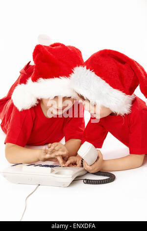 Zwei kleine Jungs in Kappen von Santa wählen eine Telefonnummer Stockfoto