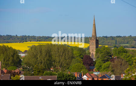 St. Johannes Kirche dominiert die Landschaft in der kleinen Stadt Bromsgrove in Worcestershire mit Feldern von Raps hinter Stockfoto