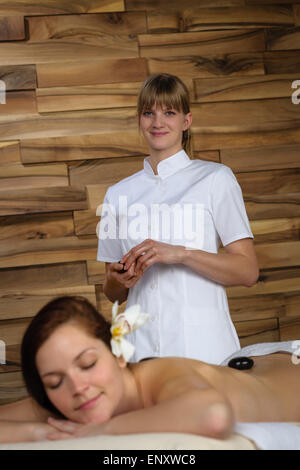 Professioneller Masseur Frau geben Massage mit Lavasteinen Stockfoto