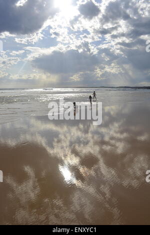 Zwischen Himmel & Erde, Kinder am Strand, Golden Beach, blauer Himmel, Sonne reflektiert, Wellen, Stockfoto