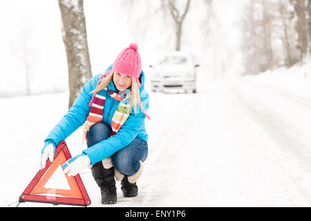 Frau setzen Warnung Dreieck Auto Aufschlüsselung winter Stockfoto