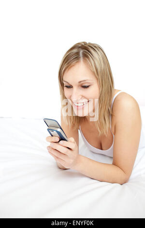 Lächelnde Frau eine SMS auf ihrem Bett liegend Stockfoto