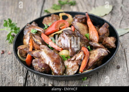 Gegrilltes Huhn Leber mit Pfeffer in Pfanne auf Holztisch, Nahaufnahme Stockfoto