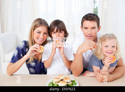 Lächelnde Familie essen Burger im Wohnzimmer Stockfoto