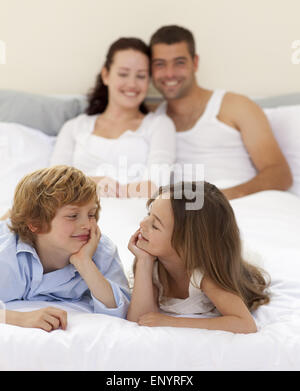 Bruder und Schwester sahen einander im Bett mit ihren Eltern Stockfoto