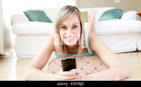 Fröhliche Frau, die einen Text auf dem Boden liegend Stockfoto