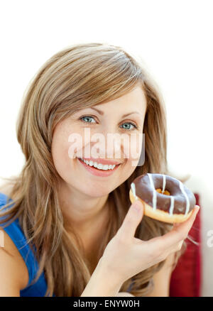 Freuen uns Frau isst einen Donut auf dem sofa Stockfoto