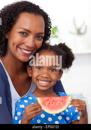 Lächelnde Mutter und ihre Tochter essen Obst Stockfoto