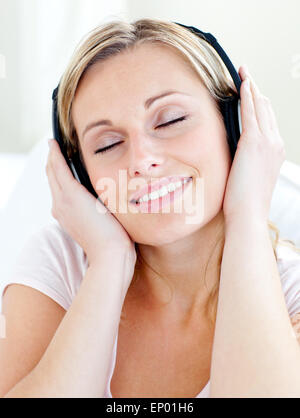Strahlende junge Frau Musik mit Kopfhörern anhören Stockfoto