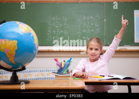 Niedliche Schulmädchen hob ihre Hand auf eine Frage Antworten Stockfoto