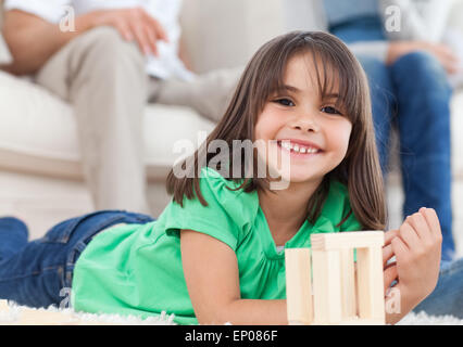 Niedliche kleine Mädchen spielen mit Dominosteinen im Wohnzimmer Stockfoto