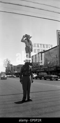 Ein Mann Steht Auf Einer Straße in Las Vegas, Nevada, USA, 1954, Im Hintergrund sterben Cowboy Neonfigur des Casinos "Westerner" Stockfoto