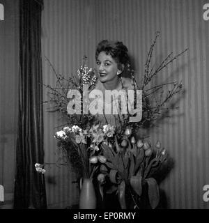 Die deutsche Sängerin und Tänzerin, Fictitious character Evelyn Künneke hinter Blumensträußen, Deutschland 1956. Die deutsche Schauspielerin, singe Stockfoto