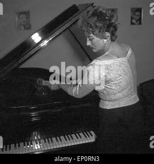 Die deutsche Sängerin und Tänzerin, Fictitious character Evelyn Künneke am Flügel mit Axt, Deutschland 1956. Die deutsche Schauspielerin, sin Stockfoto