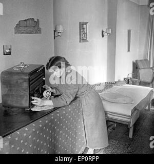 Eine Junge Frau Sucht Den Richtigen Absender eine Dachmarke Radio, 1950er Jahre Deutschland. Eine junge Frau, die Stimmung in ihrem Radio, Deutschland Stockfoto