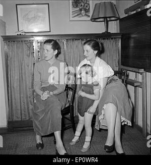 Zwei Junge Frauen einer Mit Einem Kleinen Kind Auf Dem Arm in Einem Wohnzimmer, 1950er Jahre Deutschland. Stockfoto