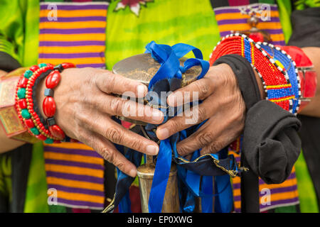 Afroamerikanische Frau Hände halten Glocken mit blauen Bändern umgeben von traditionellen Kleidung und Armbänder in Baltimore, Mar Stockfoto