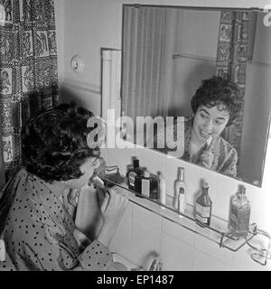 Deutsche e im Badezimmer vor dem Spiegel und putzt sich die Zähne, Deutschland 1950er Jahre. Deutsche, die in der Badewanne Stockfoto