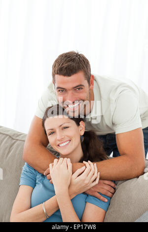 Glücklicher Mann umarmt seine Freundin auf dem Sofa sitzen Stockfoto