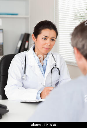 Hübschen weiblichen Arzt einen Patienten genau zuhören Stockfoto