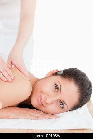 dunkelhaarige Frau, die eine Schulter Massage weiße backgroung Stockfoto