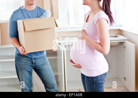 Nahaufnahme einer schwangeren Frau im Gespräch mit ihrem Mann, der die Pappe hält Stockfoto