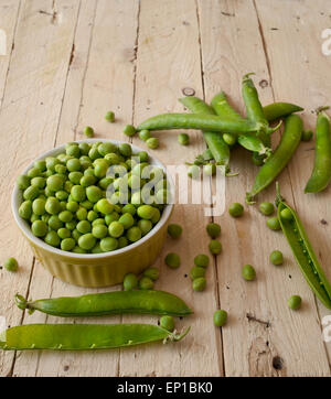 Ökologische frische grüne Erbsen Hülsen in einem rustikalen Holztisch. Stockfoto