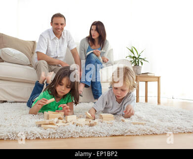Glückliche Eltern auf dem Sofa, Blick auf ihre Kinder spielen auf dem Boden Stockfoto