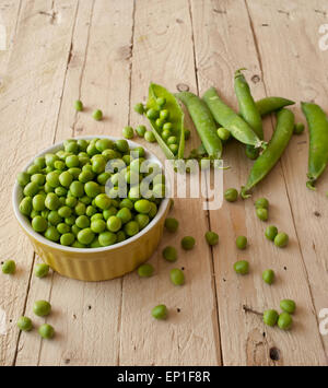 Ökologische frische grüne Erbsen Hülsen in einem rustikalen Holztisch. Stockfoto