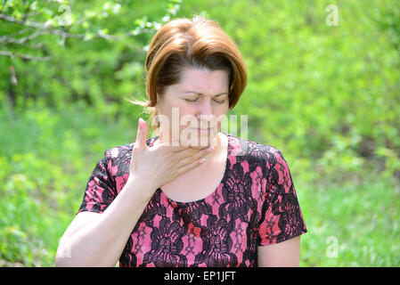 Frau mit Halsschmerzen in der Natur Stockfoto