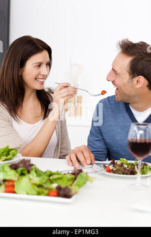 Leidenschaftliche Frau, die eine Tomate zu ihrem Freund während dem Mittagessen geben Stockfoto