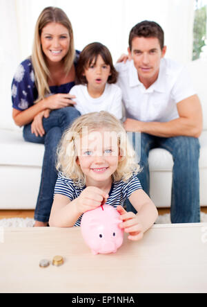 Blonde Mädchen einfügen Münze in ein Sparschwein Stockfoto